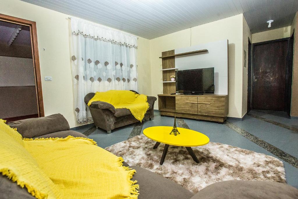 een woonkamer met een bank en een gele tafel bij Casa Grande com 2 quartos e 1 suíte in Foz do Iguaçu