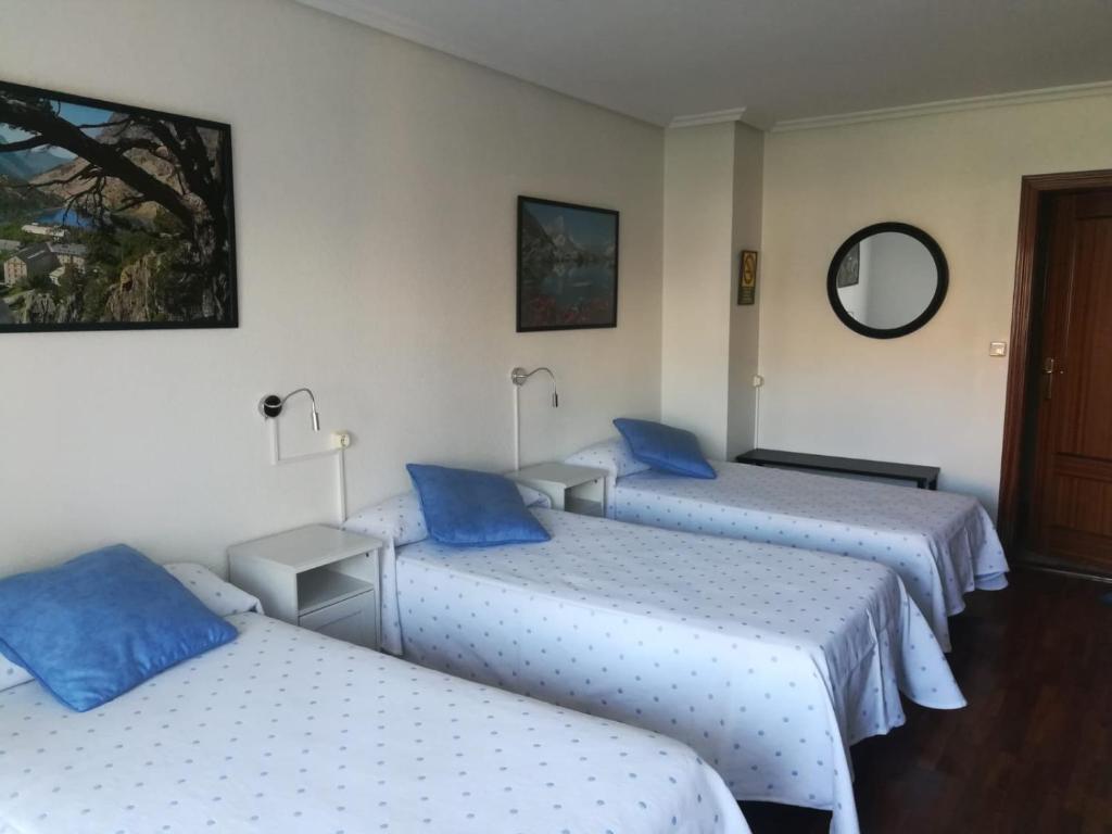 a hotel room with three beds with blue pillows at Pension Toñi in Belorado