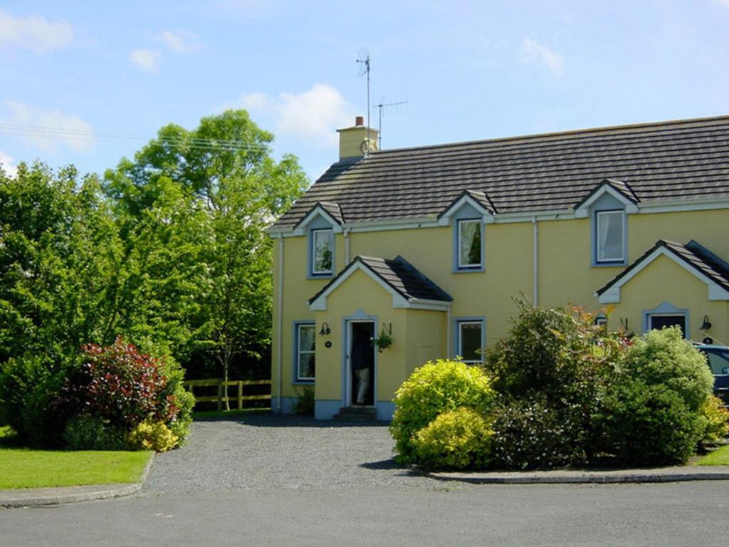 una casa amarilla con una entrada delante de ella en The Waterside Cottages en Nenagh