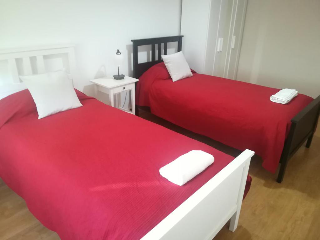 - 2 lits dans une chambre avec des draps rouges dans l'établissement Casa do Pedro - Lisbon South Bay, à Almada