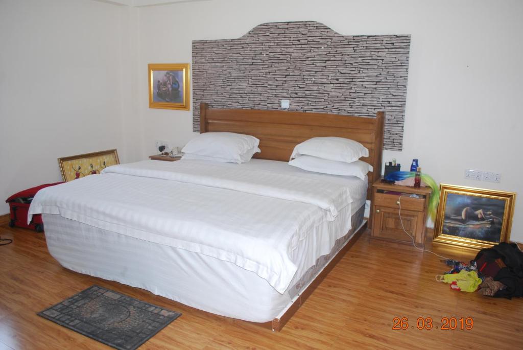 a bedroom with a large white bed and a brick wall at Ampomaah Hotel in Accra