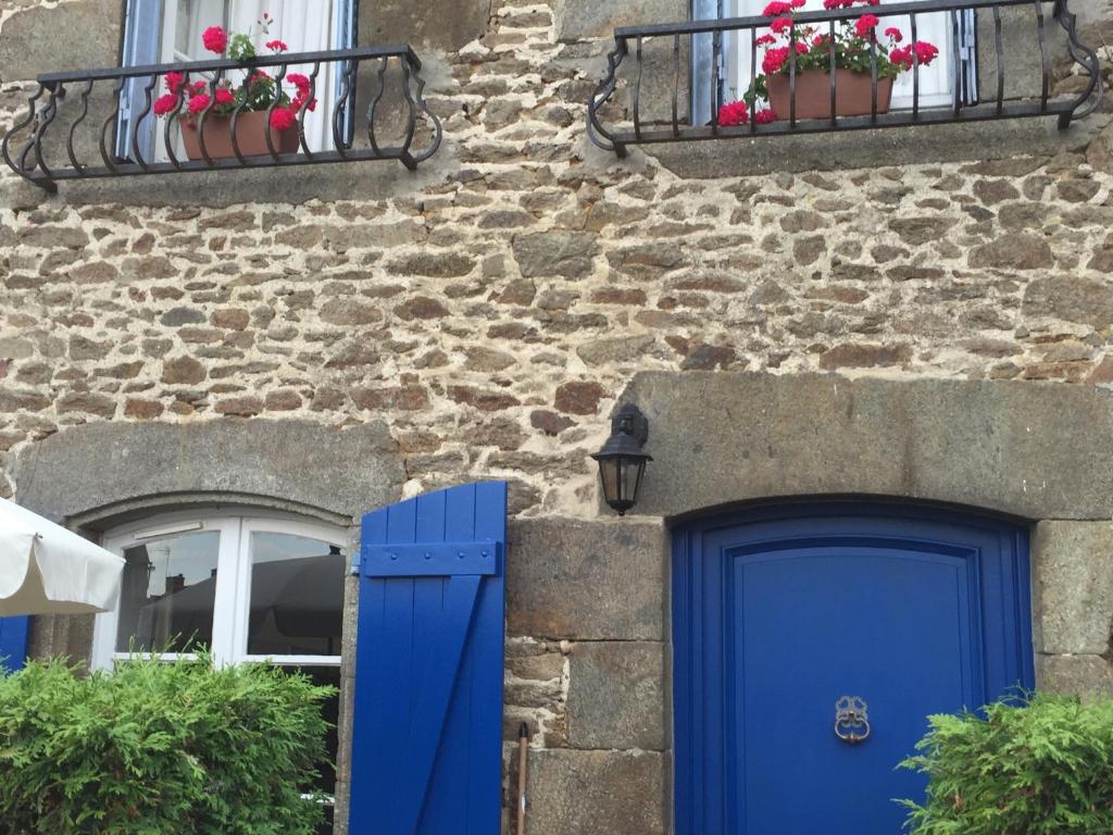 um edifício de pedra com uma porta azul e janelas em La Petite Maison Bleue em Taden