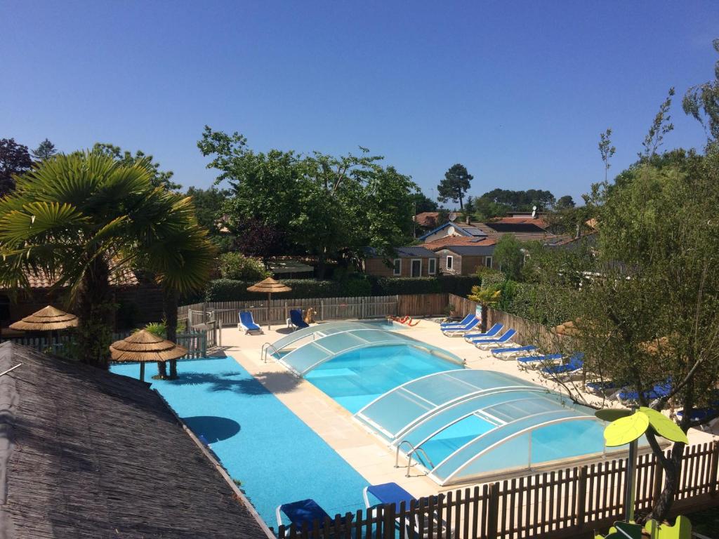 une grande piscine avec des chaises et des parasols dans l'établissement Appartement Cosy - Les Ecureuils, à Arès