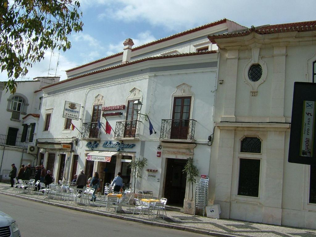 ein weißes Gebäude mit Tischen und Stühlen auf einer Straße in der Unterkunft Alentejano Low Cost Hotel in Estremoz