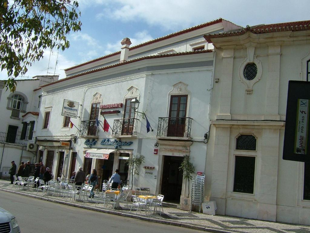 een wit gebouw met tafels en stoelen in een straat bij Alentejano Low Cost Hotel in Estremoz