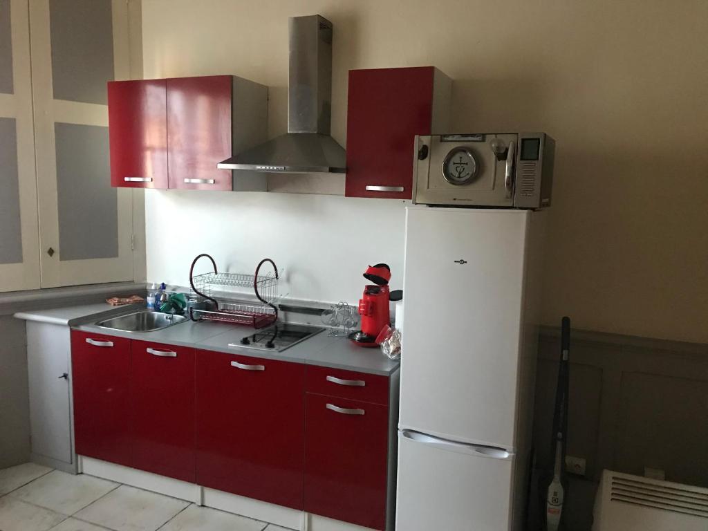 eine Küche mit roten Schränken und einem weißen Kühlschrank in der Unterkunft Studio des alpes in La Mure