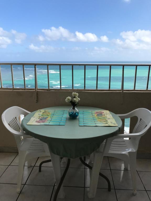 a table on a balcony with a view of the ocean at Ocean Front Apartment in Luquillo