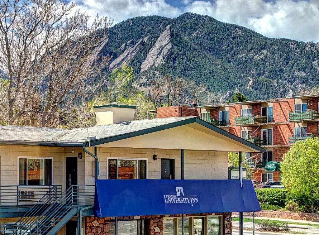 a building with a blue sign in front of a mountain at Boulder University Inn in Boulder