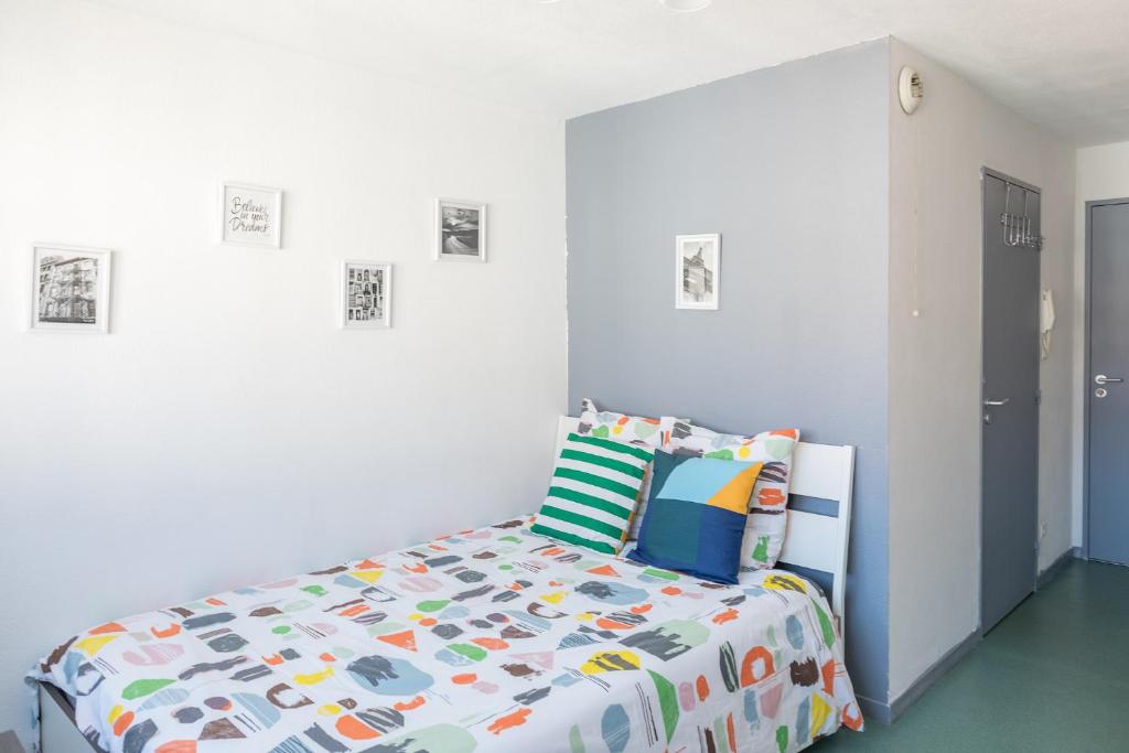 a white bedroom with a bed with a colorful comforter at Part-Dieu Lyon Appart in Lyon