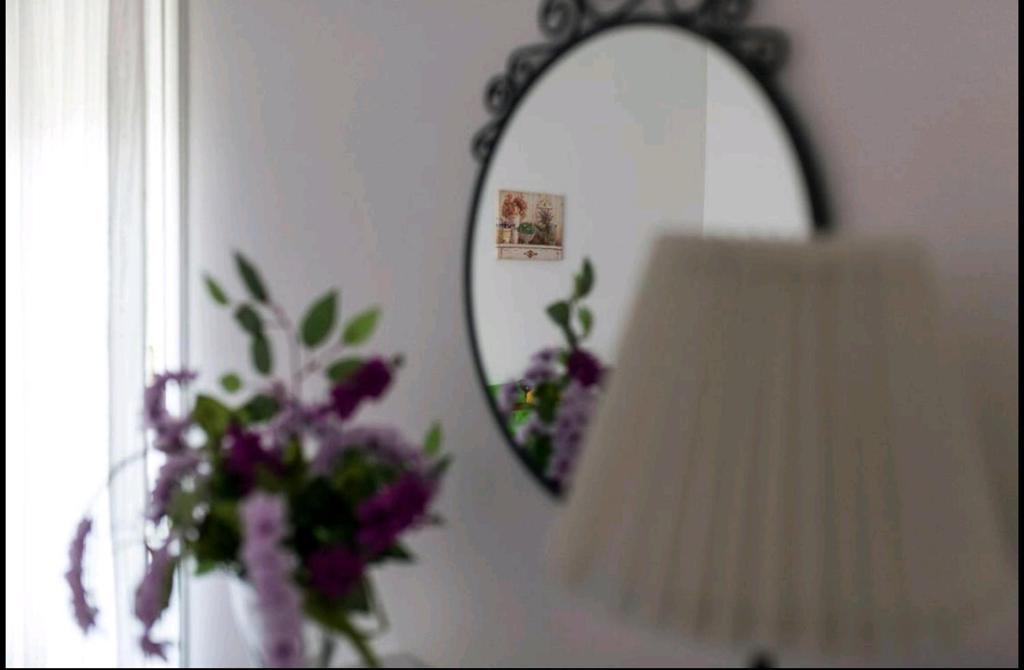 un espejo y una lámpara y un jarrón de flores en La casetta di Ilma, en Vietri
