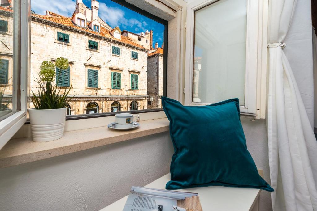 uma almofada azul sentada no peitoril da janela em Apartment 4 You em Dubrovnik