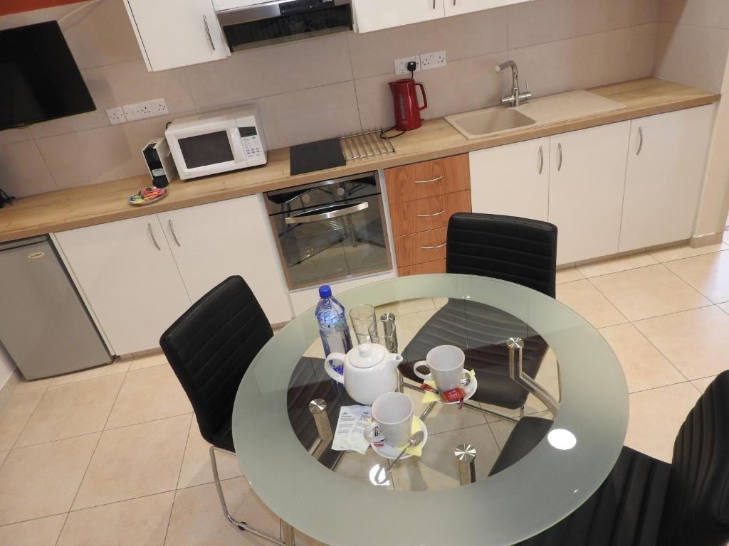 a kitchen with a glass table and black chairs at Hill View Hotel Apartments in Pissouri