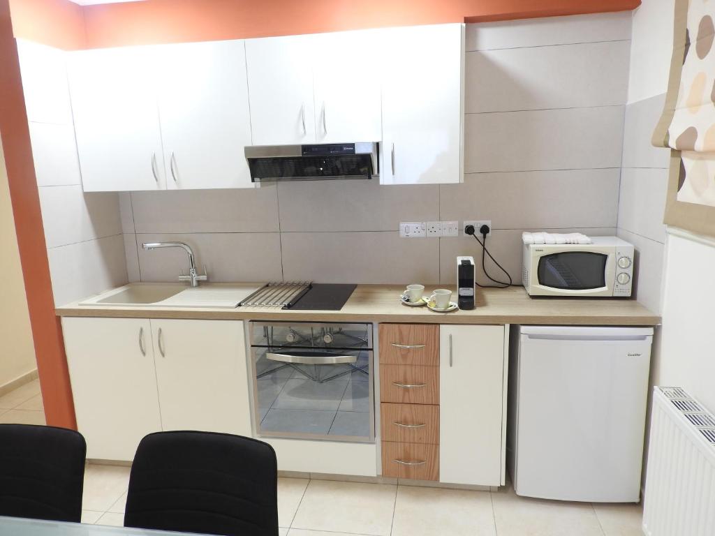a small kitchen with white cabinets and a microwave at Hill View Hotel Apartments in Pissouri