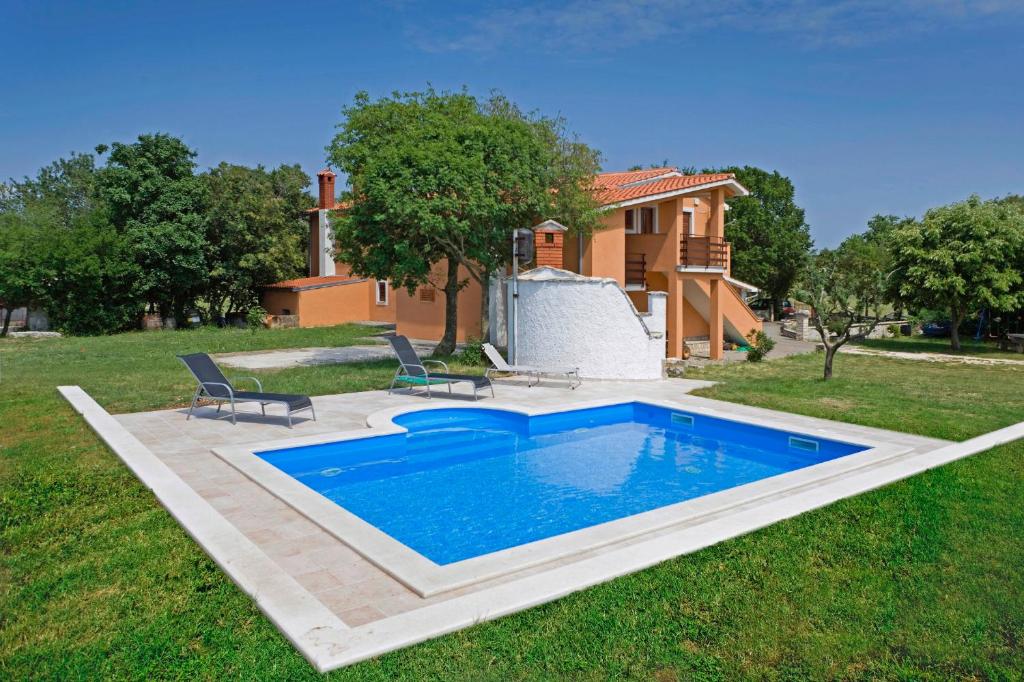 una piscina in un cortile con due sedie e una casa di Vrtline in Krnica * Istrien a Krnica