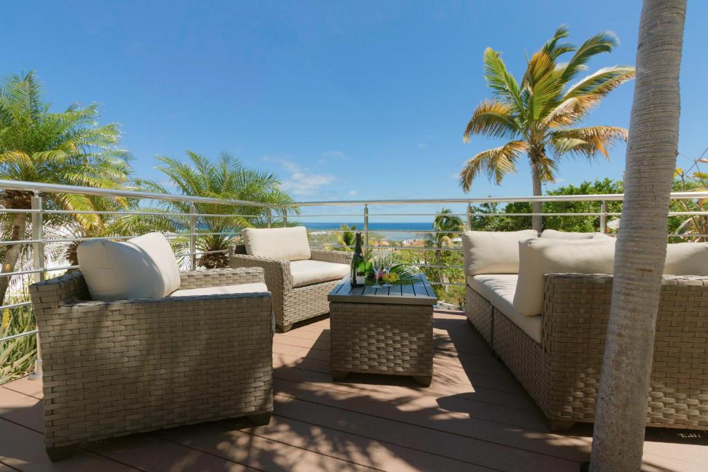 un patio con sillas de mimbre, palmeras y el océano en VILLA SAPHIR, en Saint Martin