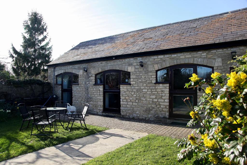 a brick building with a table and chairs in front of it at Stable Cottage, Oxfordshire in Oxford