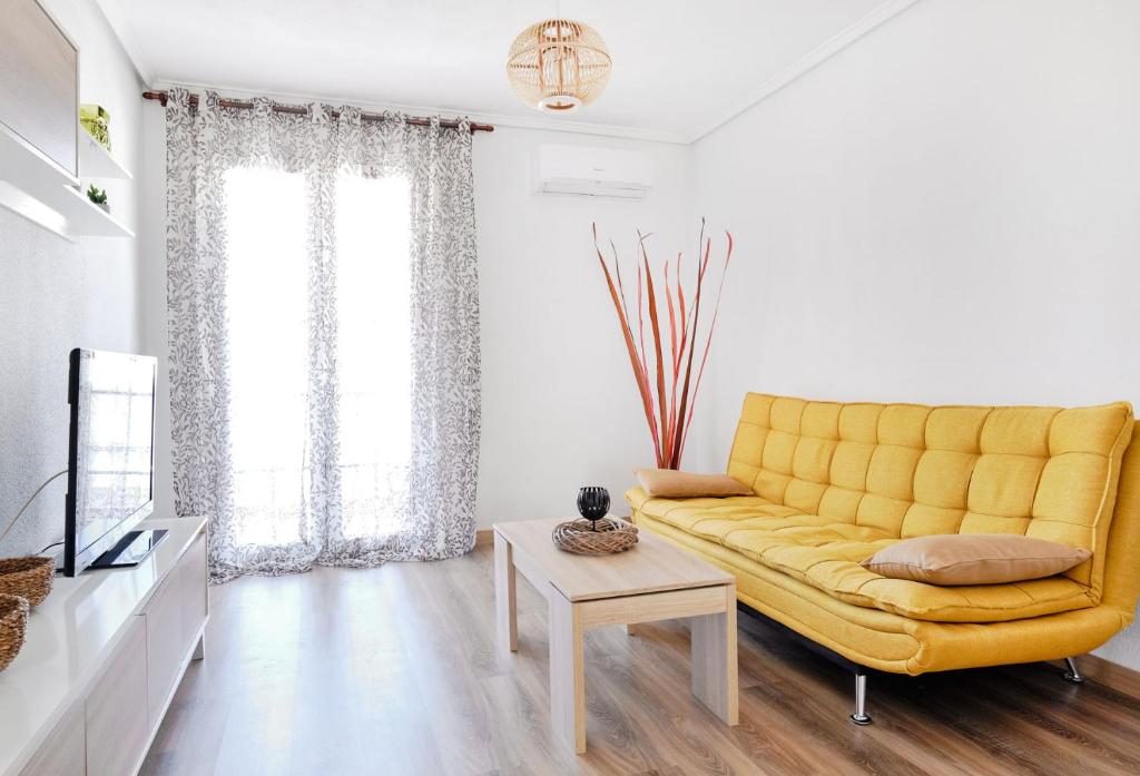 a living room with a yellow couch and a tv at Pueblito La Zenia Beach in Orihuela Costa