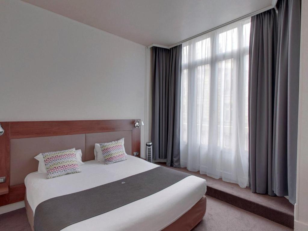 a hotel room with a bed and a large window at Campanile Orléans Centre Gare in Orléans