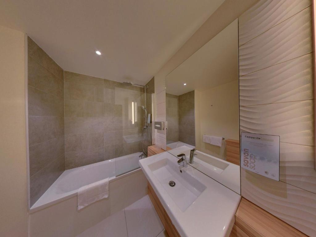 a bathroom with a tub and a sink and a bath tub at Campanile Orléans Centre Gare in Orléans