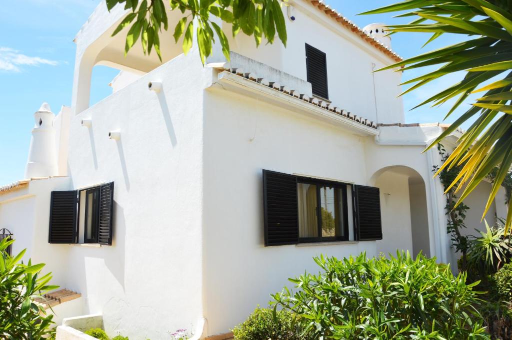 a white house with black shutters on it at Casa Maricel in Praia do Carvoeiro