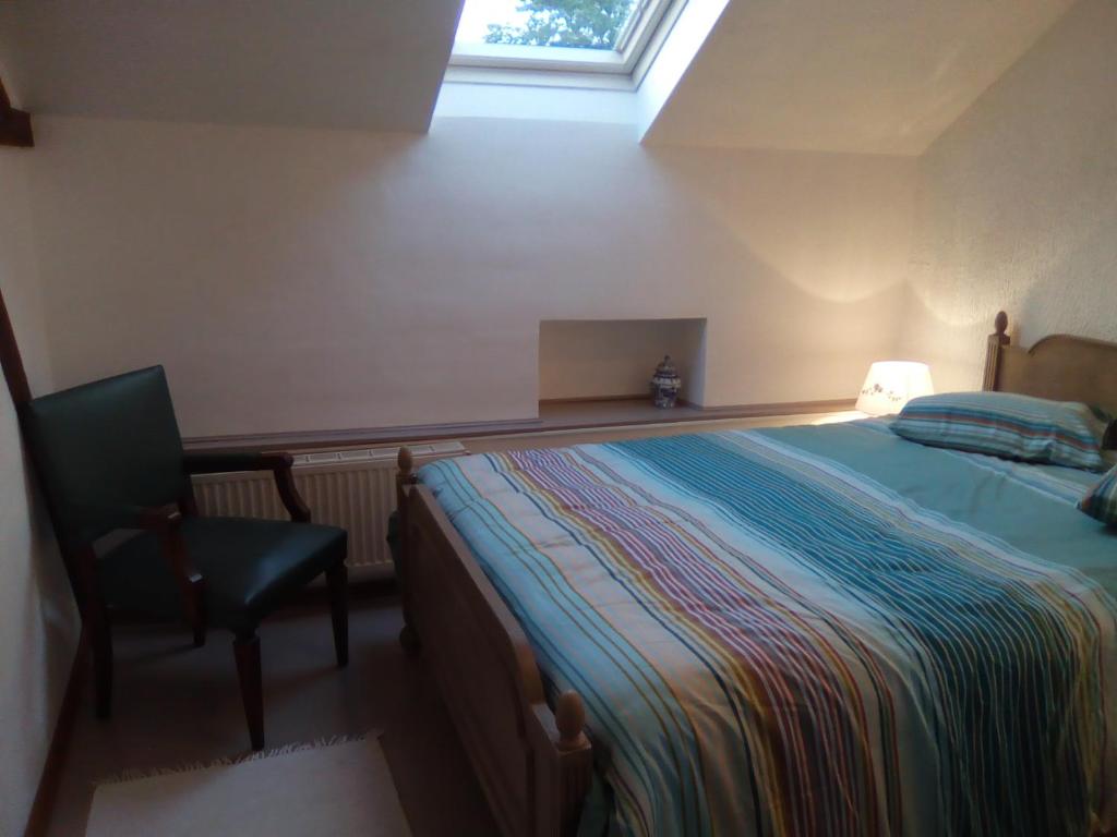 a bedroom with a bed and a chair and a window at Le Clos Fleuri in Sautin