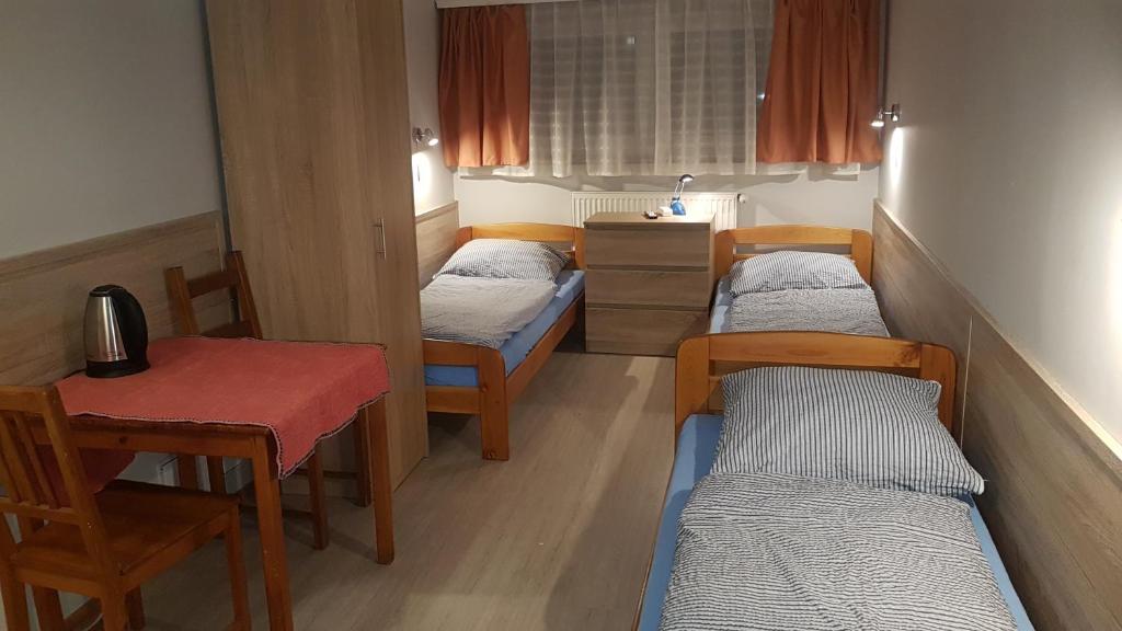Cette chambre comprend 3 lits, une table, une table et des chaises. dans l'établissement Noclegi Silesia, à Tychy