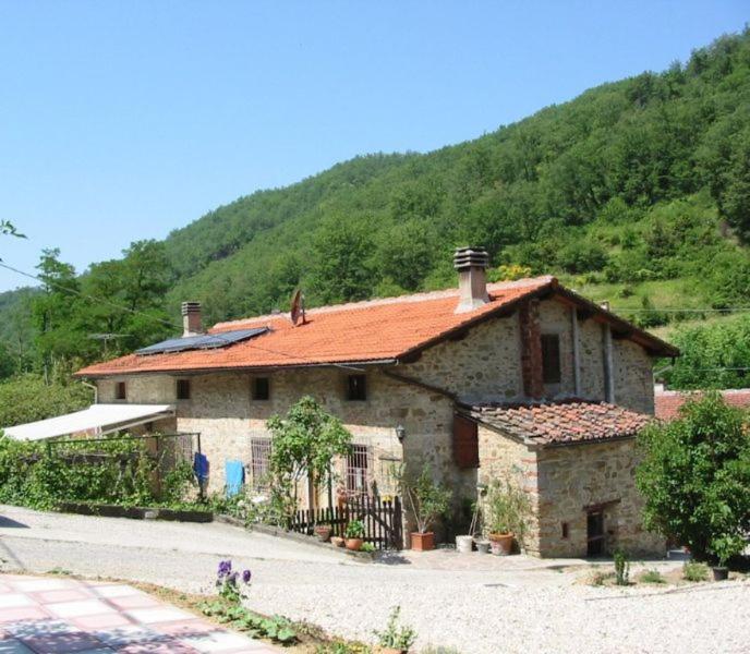 kamienny dom z czerwonym dachem przed górą w obiekcie Casa Botena w mieście Vicchio