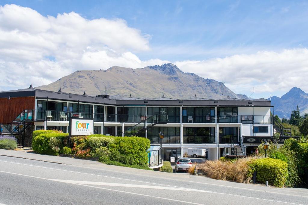 a building on the side of a road with a mountain at Four Seasons Motel in Queenstown