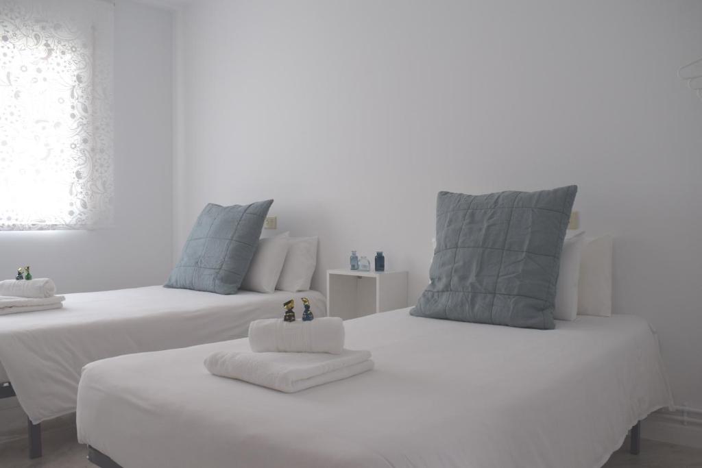 two white beds with towels on them in a room at La Casa de Manuel in Portomarin