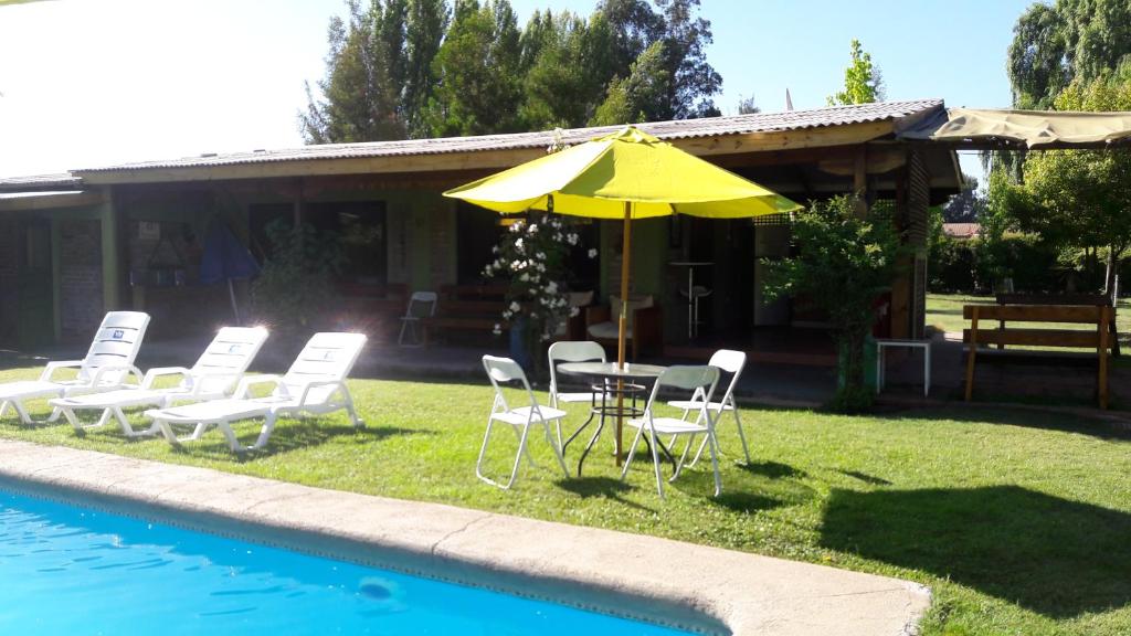 - une table et des chaises avec un parasol à côté de la piscine dans l'établissement Cabaña Campestre de 1 Ambiente En Paine, à Paine