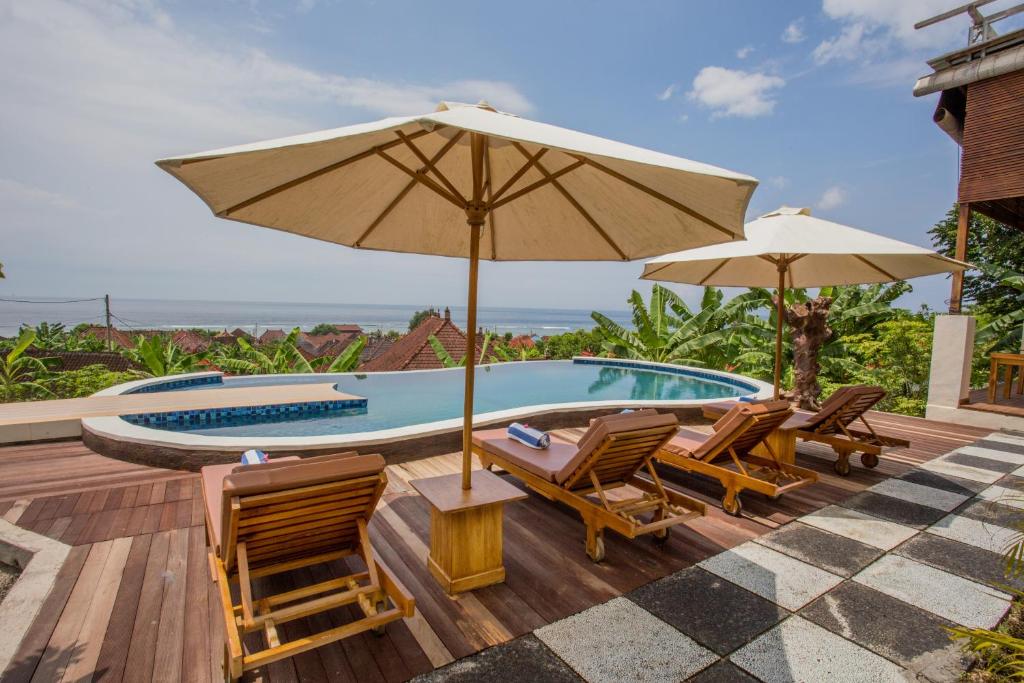 a deck with chairs and an umbrella and a swimming pool at Horizon Nusa Penida in Nusa Penida