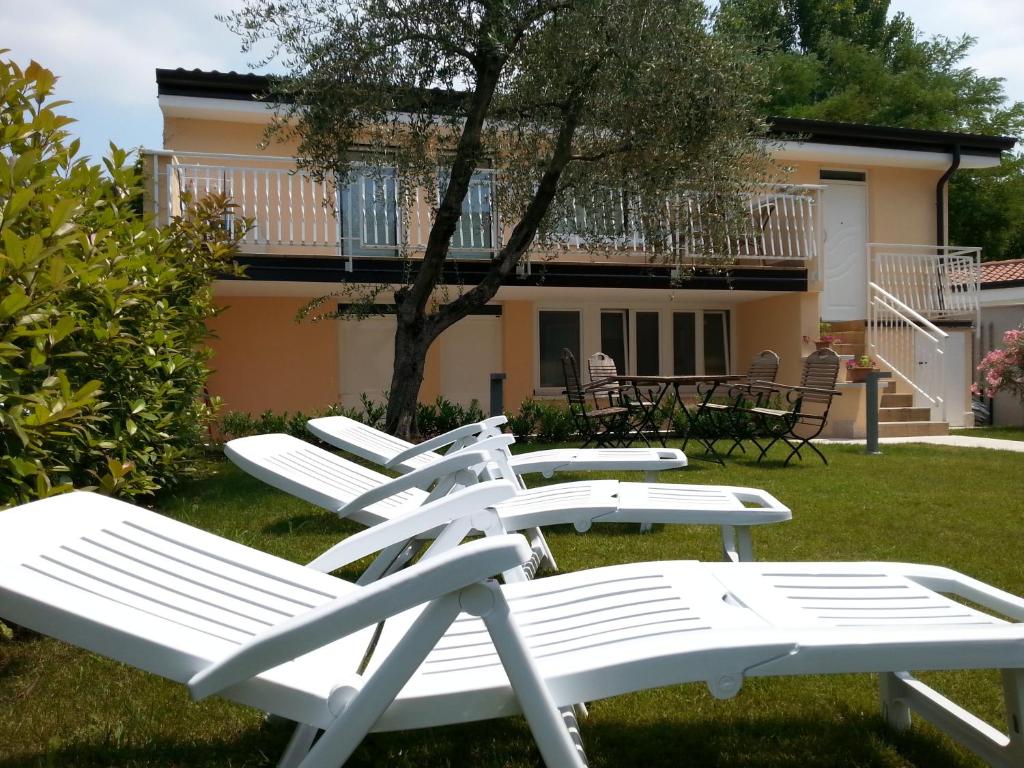 una fila de sillas blancas en el césped en Appartamento Villa Elison, en Lazise