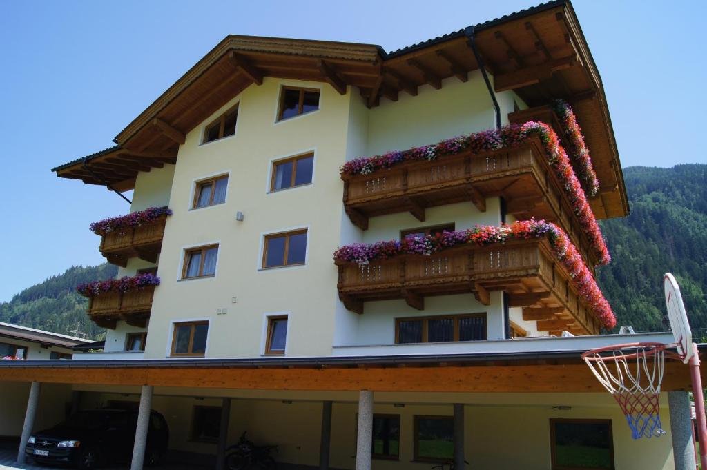 a building with flowers on the balconies and a basketball hoop at Apparthotel Stoanerhof in Uderns