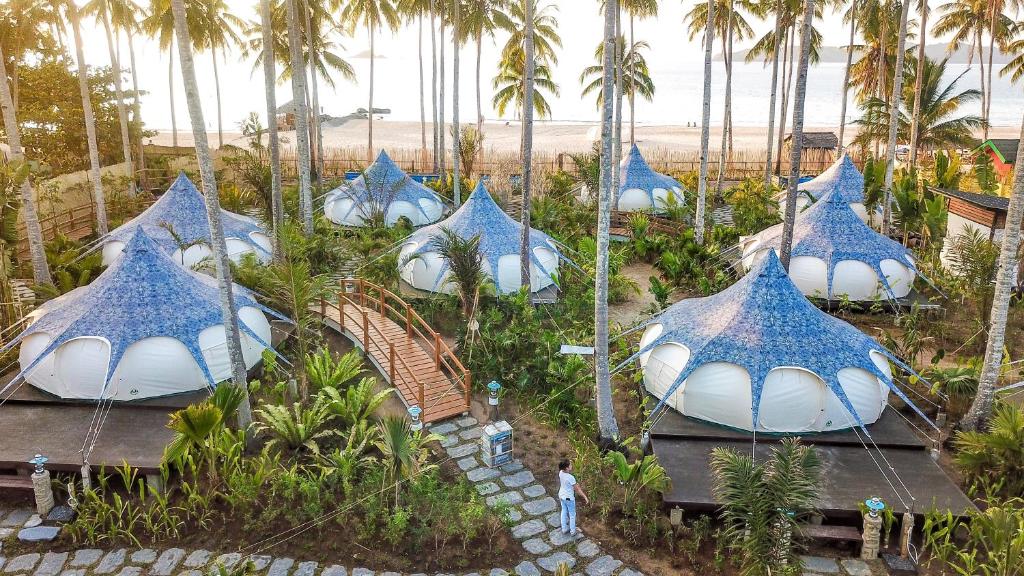 a row of palm trees with umbrellas at Nacpan Beach Glamping in El Nido