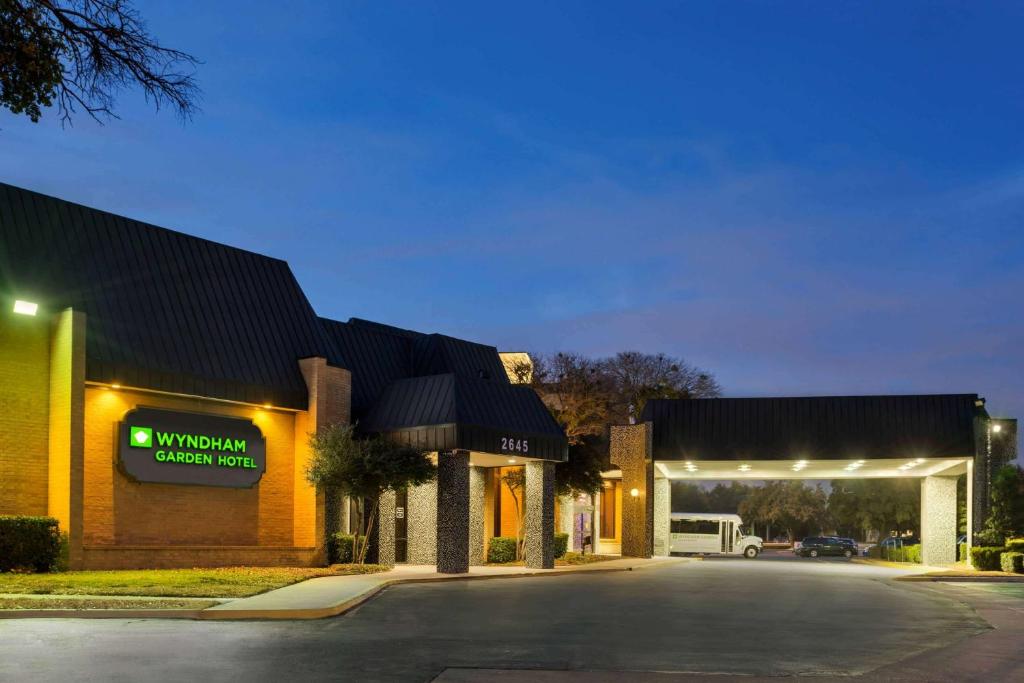 un edificio con una señal que lee la parrilla de pollo de la sabiduría en Wyndham Garden Dallas North, en Dallas