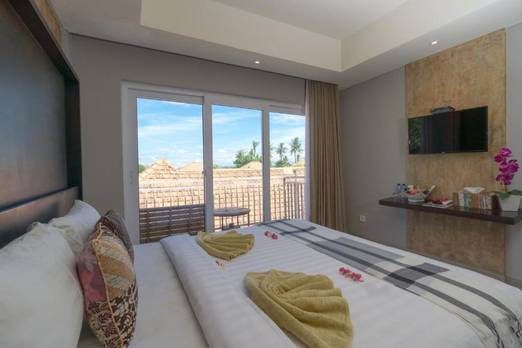 a bedroom with a large bed with a balcony at Locomotive Hotel and Spa by EPS in Nusa Lembongan