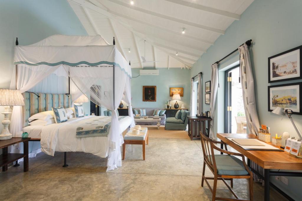 a bedroom with a canopy bed and a desk at Kahanda Kanda in Koggala