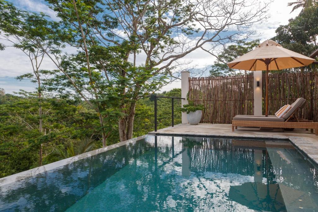 a swimming pool with an umbrella and a chair and an umbrella at Kahanda Kanda in Koggala