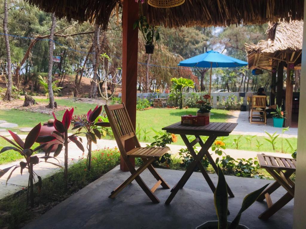 um pátio com uma mesa, cadeiras e um guarda-sol em Hoi An Blue Seaside Homestay em Dien Ban