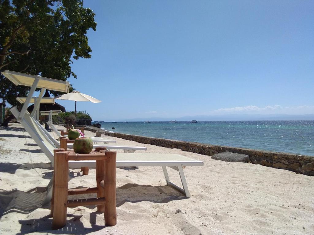 a table and chairs on a beach with the ocean at Ancelle Cristo Re in Moalboal