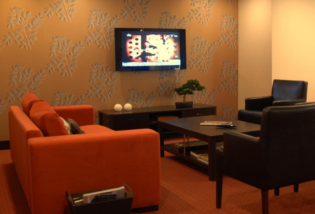 a living room with orange furniture and a tv on the wall at Silivri Park Hotel in Silivri