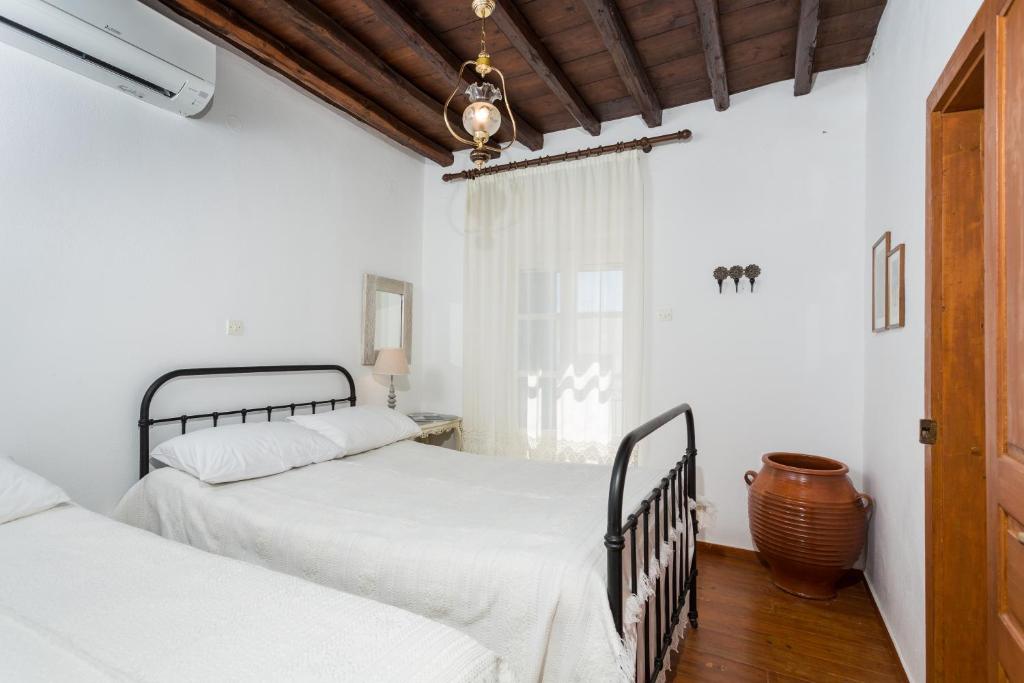 MárpissaにあるMarouso Villa Parosの白い壁とウッドフロアのベッドルーム1室(ベッド2台付)
