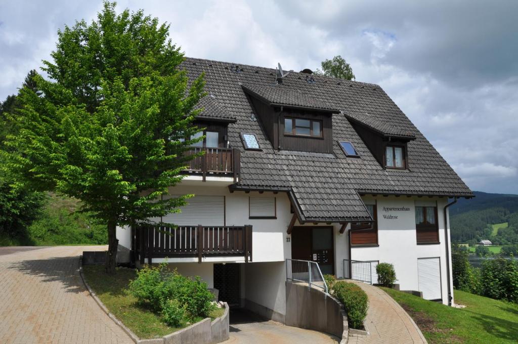 uma casa branca com um telhado de gambrel em Appartements Waldrose em Titisee-Neustadt