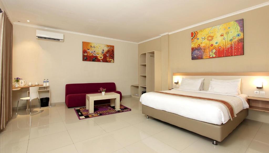 a bedroom with a bed and a red chair at Laxston Hotel in Yogyakarta