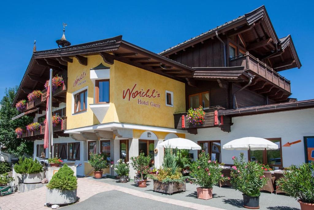 un edificio con plantas y sombrillas delante de él en Noichl’s Hotel Garni, en Sankt Johann in Tirol