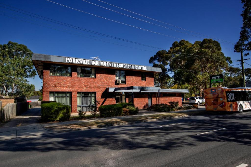 - un bâtiment en briques rouges dans une rue avec un bus dans l'établissement Parkside Inn Motel, à Melbourne