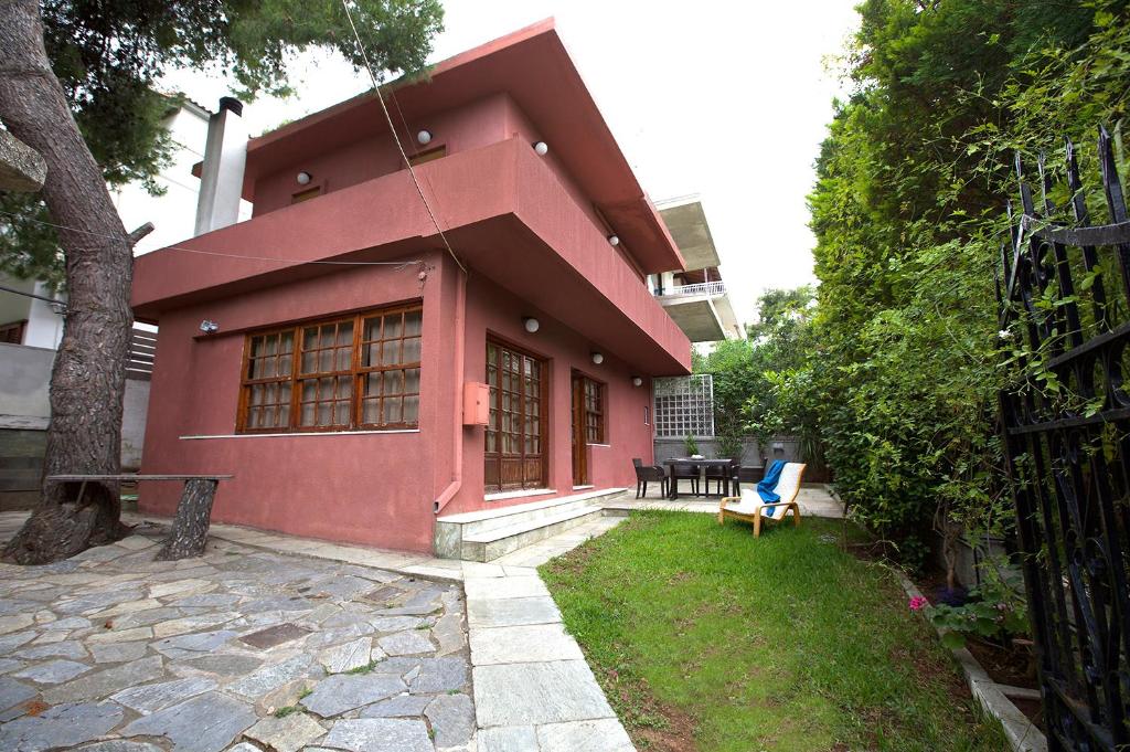 une maison rouge avec une table et une chaise dans la cour dans l'établissement Villa House 200m From Sea, à Áyios Andréas