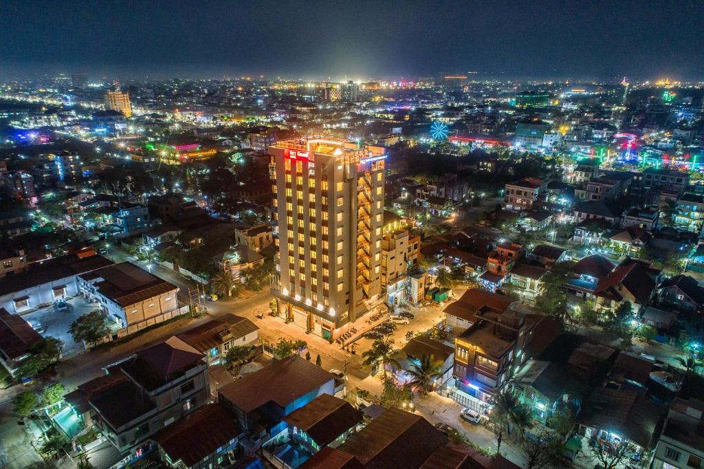 una città di notte con un palazzo alto di Ritz Grand Hotel Mandalay a Mandalay