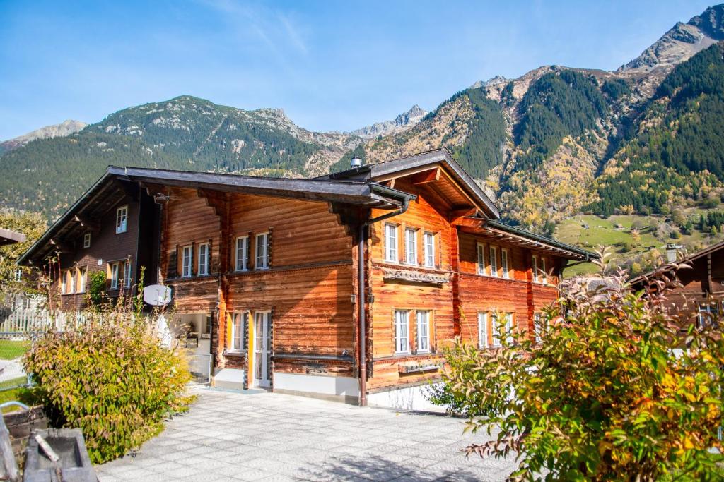 a large wooden house with mountains in the background at Chalet Guttannen EG - GriwaRent AG in Guttannen