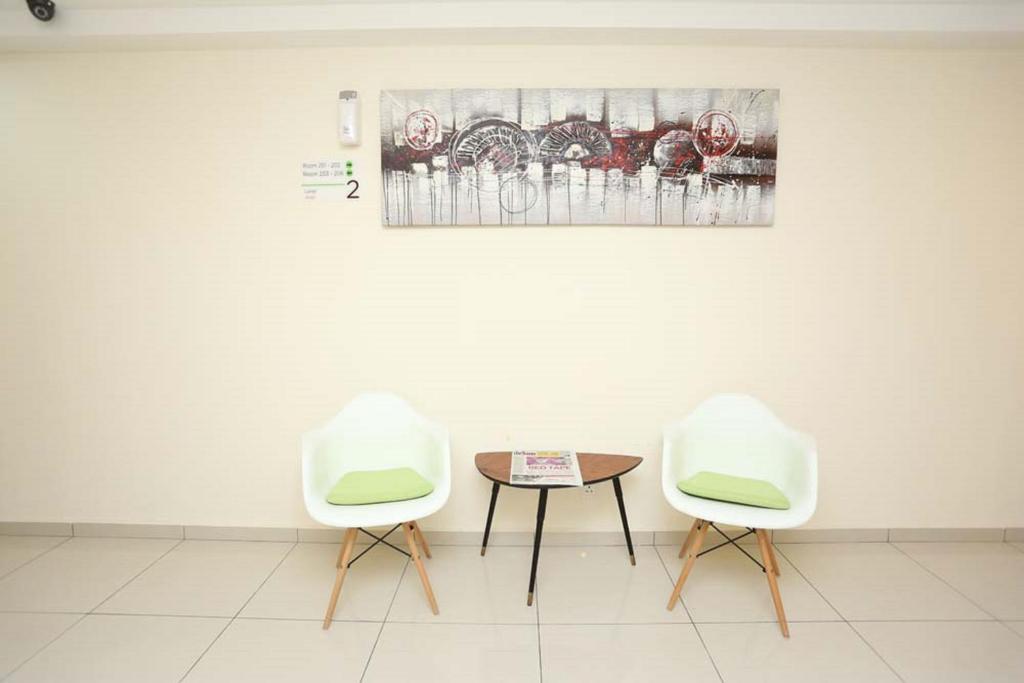 Two white lounge chairs and a small round table arranged against a decorated wall.